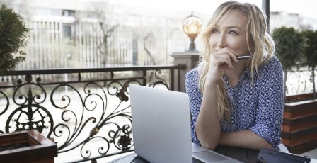 Female blogger working in coffee shop, using laptop