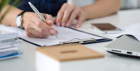 Person writing notes on a clipboard