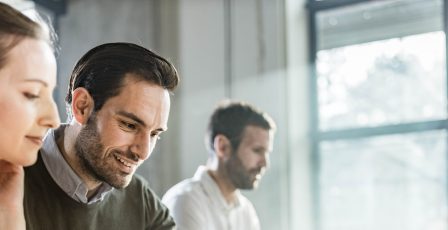 Happy business colleagues cooperating while working on laptop during a meeting