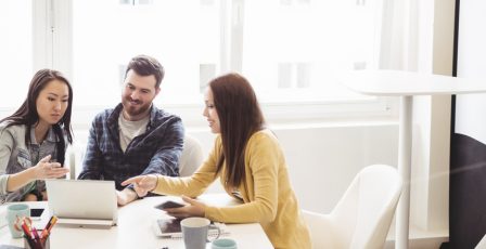 Group of colleagues gathered around a laptop