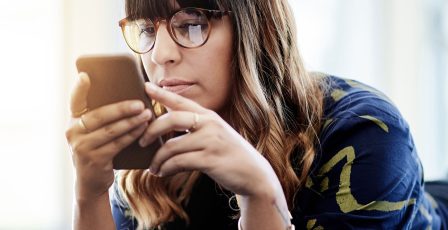 Young woman online gaming using her mobile phone