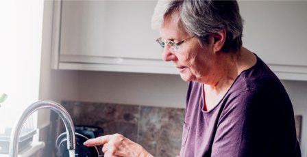 Woman pouring water into a kettle in the kitchen