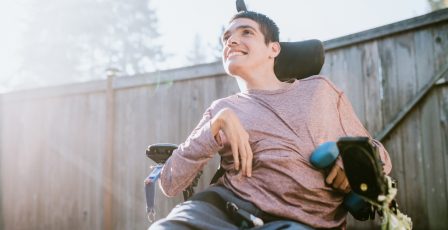 Young adult in a wheelchair smiling outdoors