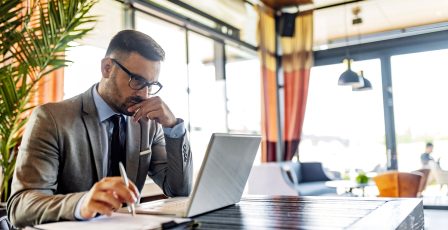 Businessperson working on laptop while making notes