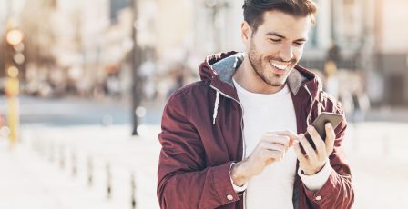 Man gaming and texting on his phone in the street