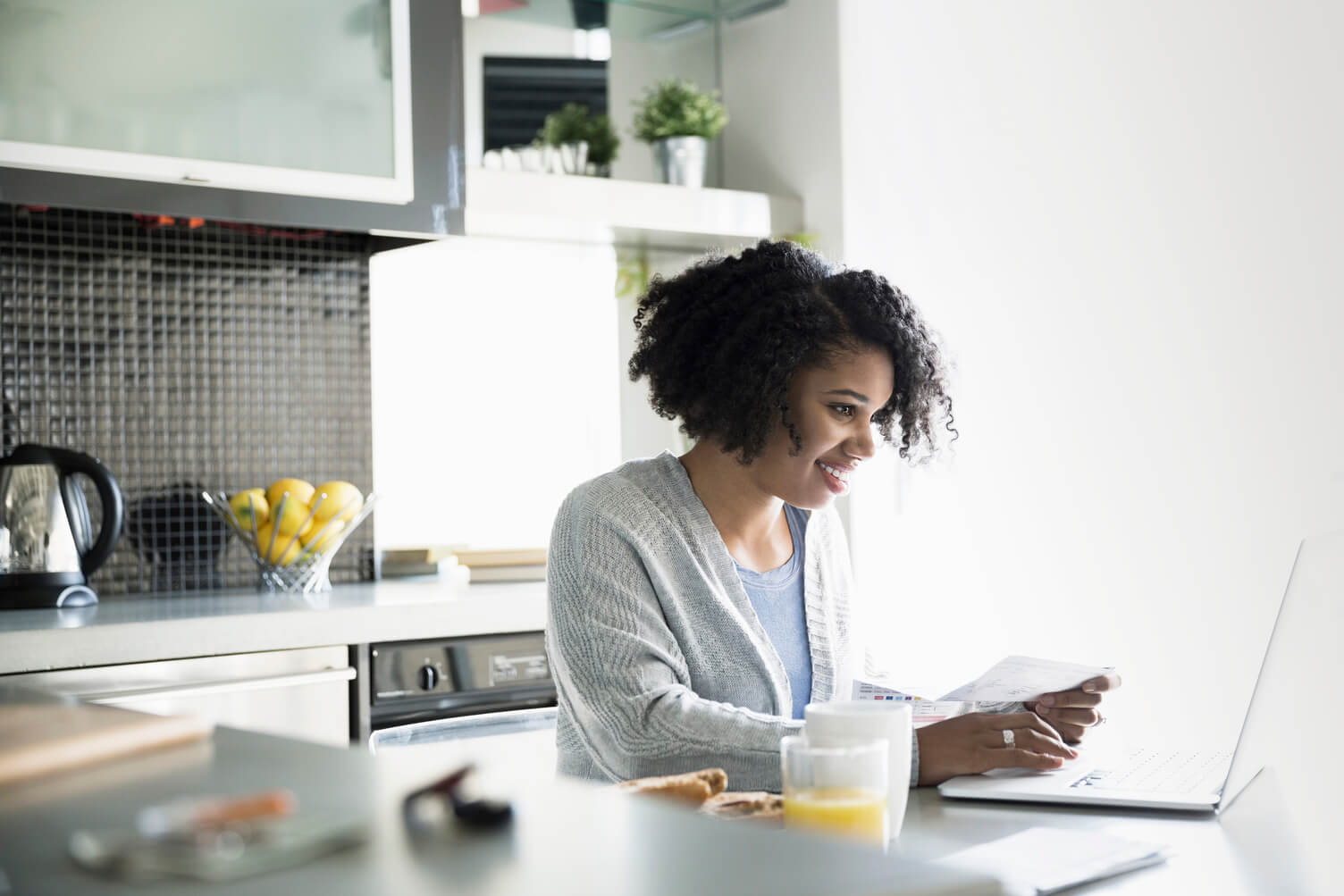 Woman in her kitchen browing on a laptop.