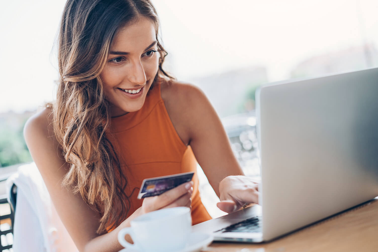 Woman holding a credit card and looking at her computer