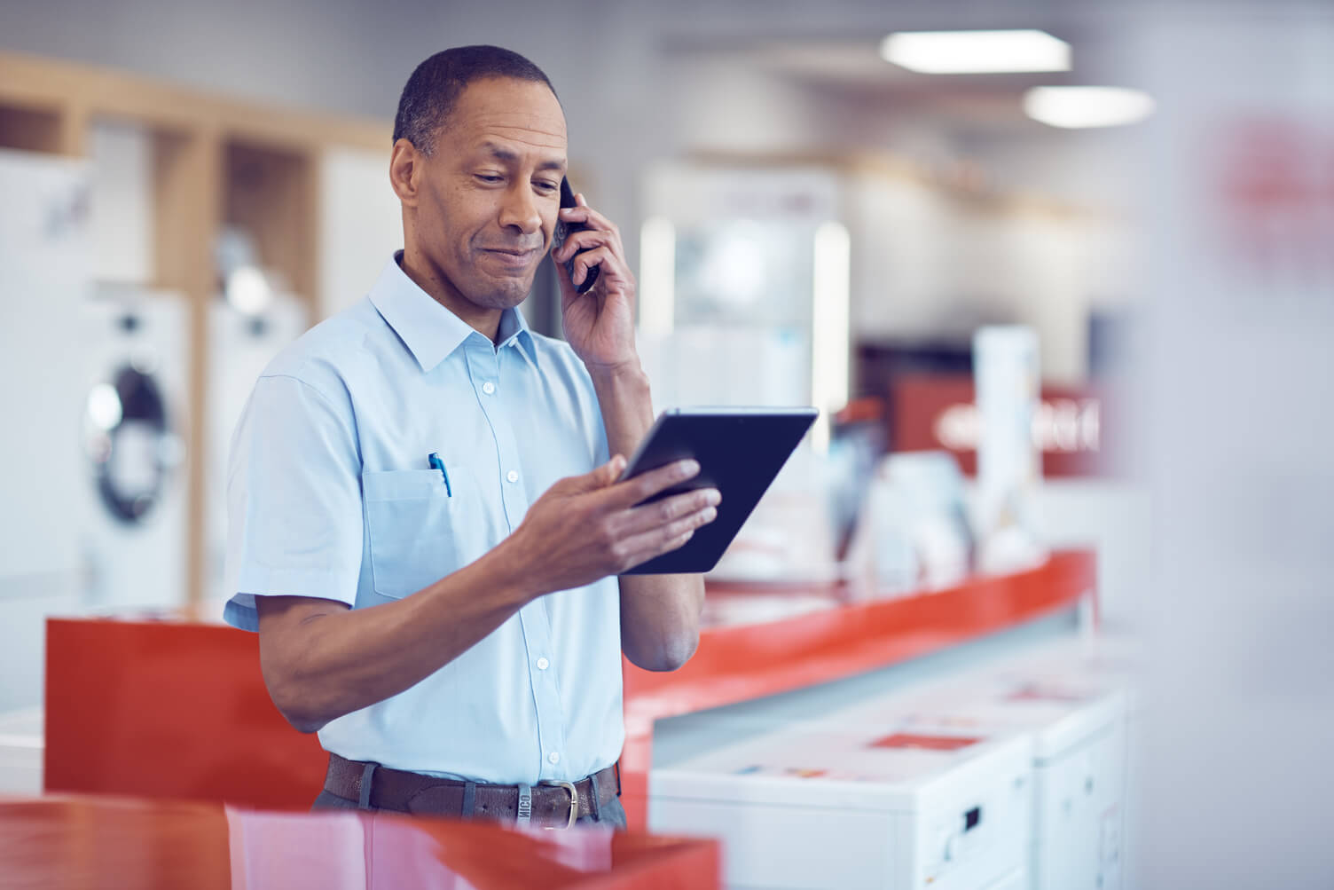 Man on the phone looking at a tablet