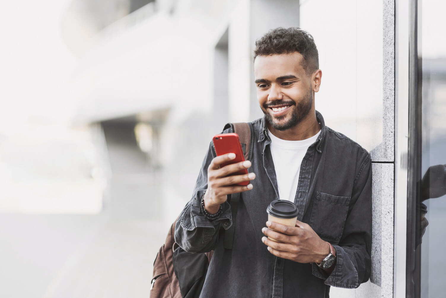 Man smiling while looking his phone outside