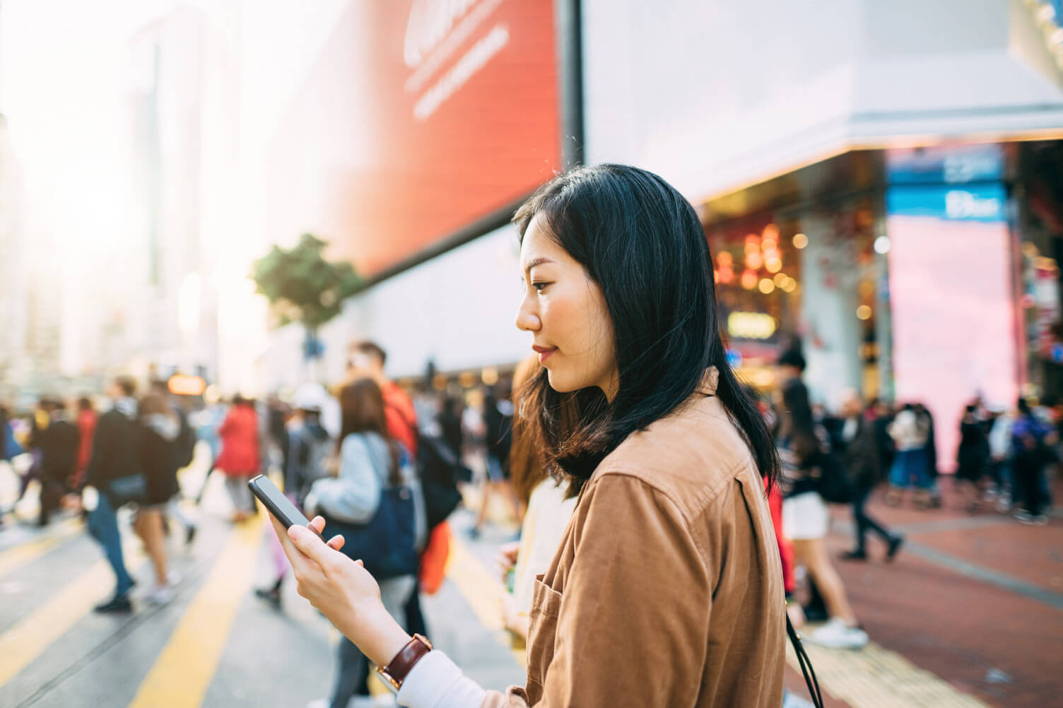 Woman looking at her phone while crossing the street