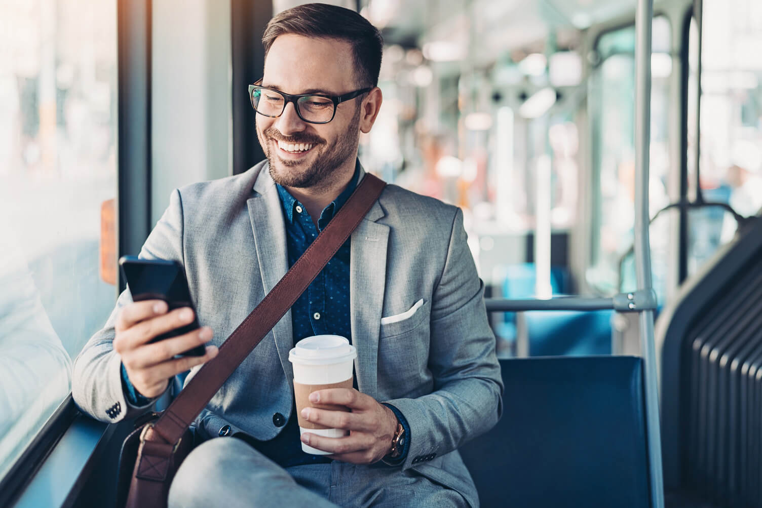 Man smiling while looking his phone on a bus