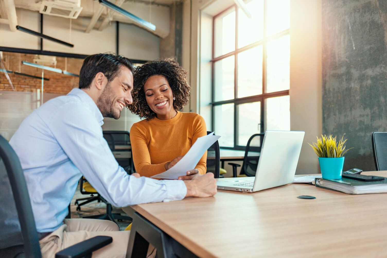 A man and woman sat down and smiling looking at a document