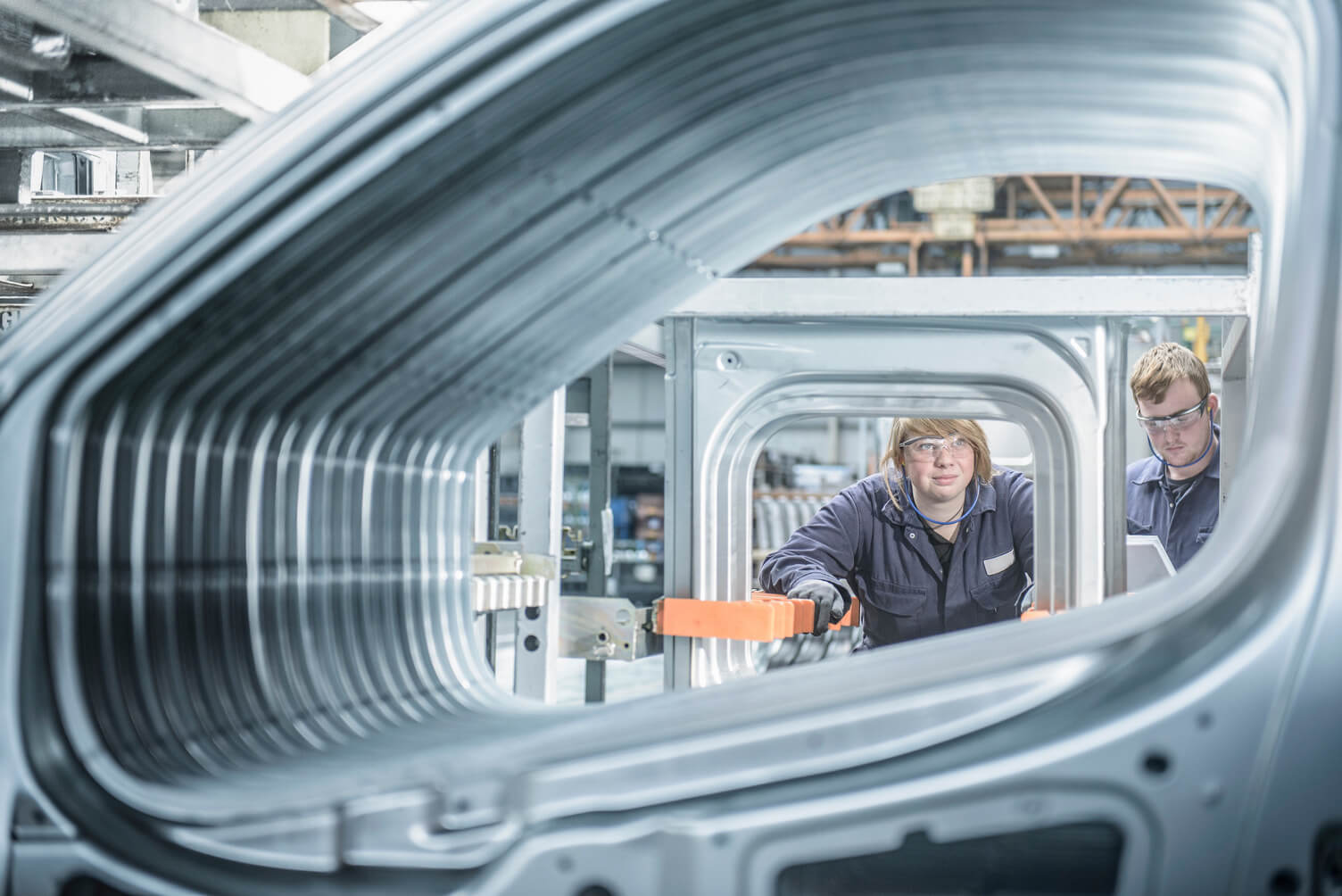 a person in a car manufacturing warehouse looking through a row of car windows