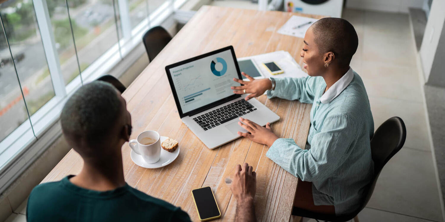 Two colleagues looking over data on a laptop