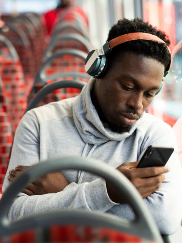 Young man on a bus looking at his emails on his mobile phone