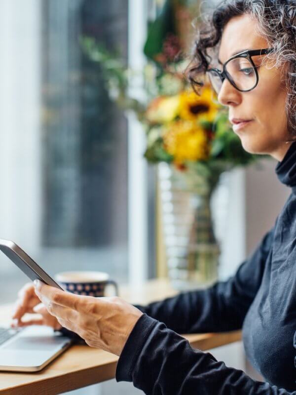 Woman sat having a coffee while browsing on phone