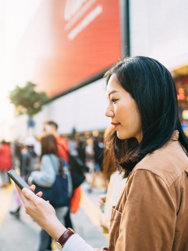 Woman looking at phone in a busy street