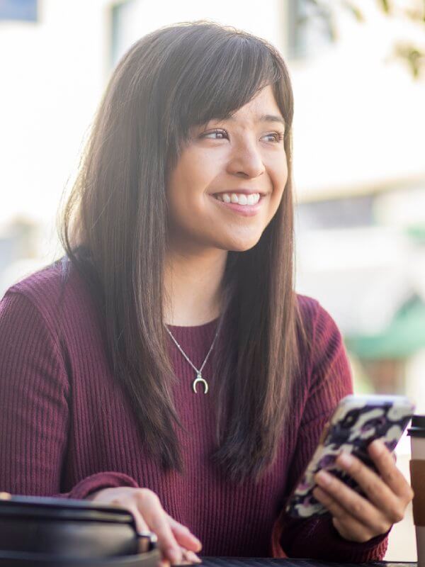 Young woman smiling while using her mobile phone