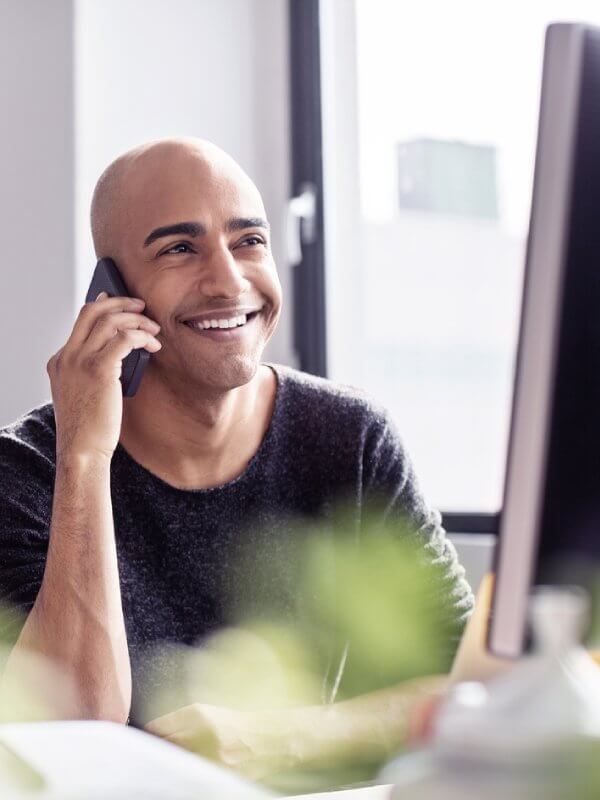 Man smiling while talking on the phone