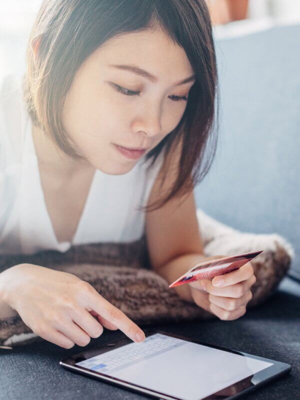Young woman at home using her credit card on her tablet
