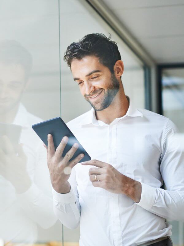 Man smiling while looking at a tablet