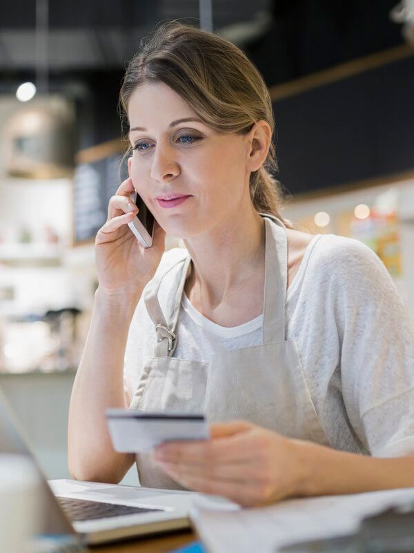 Woman holding her credit card while on the phone to a bank