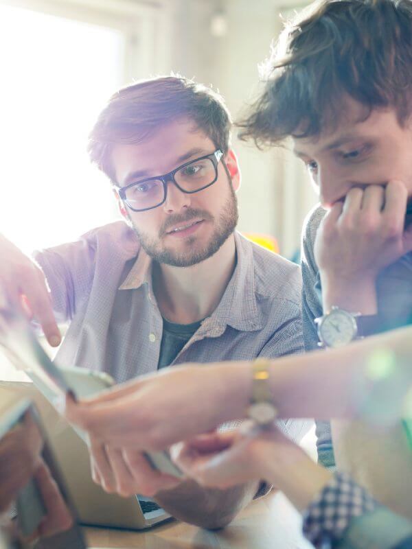 Group of colleagues gathered around a computer looking at marketing data