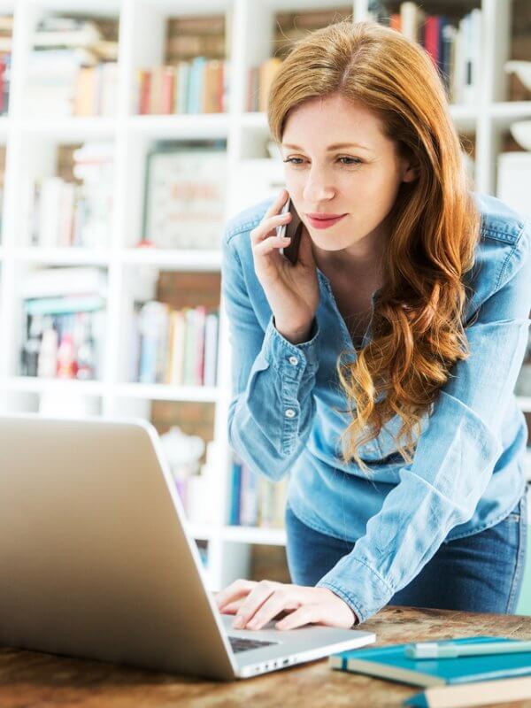 Woman on phone in office using a laptop