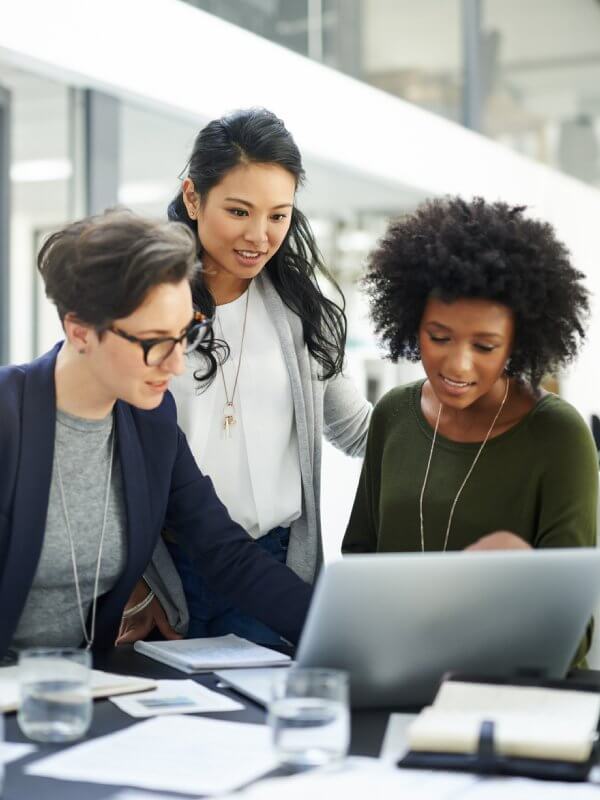 Group of colleagues gathered around a computer looking at fraud data