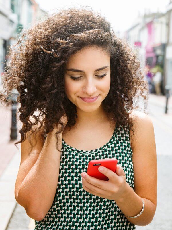 Young woman smiling at her mobile phone