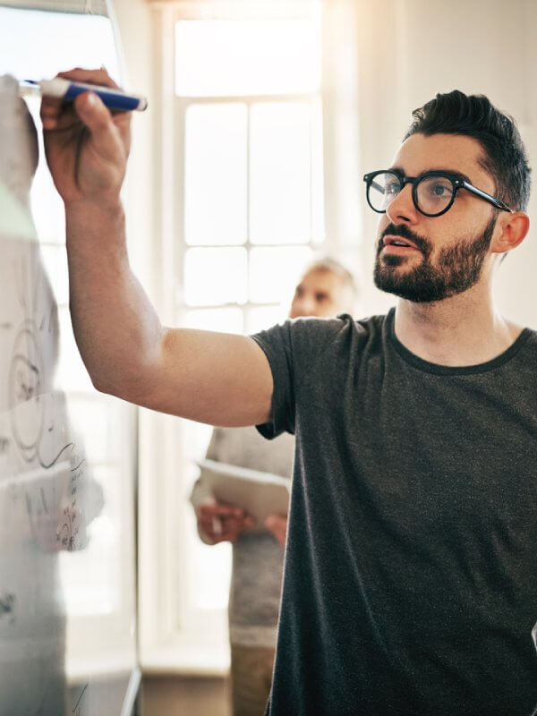 Team leader writing on a whiteboard during a presentation