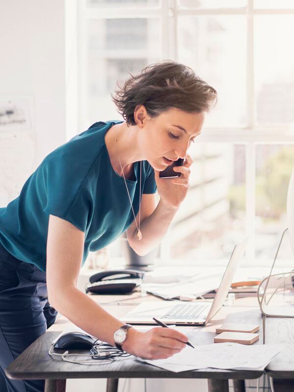 Woman writing notes in a notepad on a telephone call