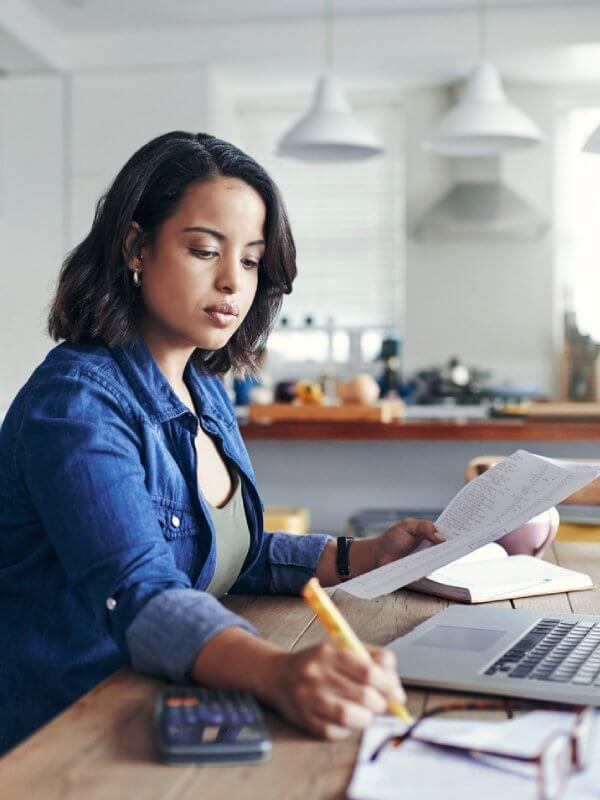 Woman making risk policy notes in notepad from her laptop