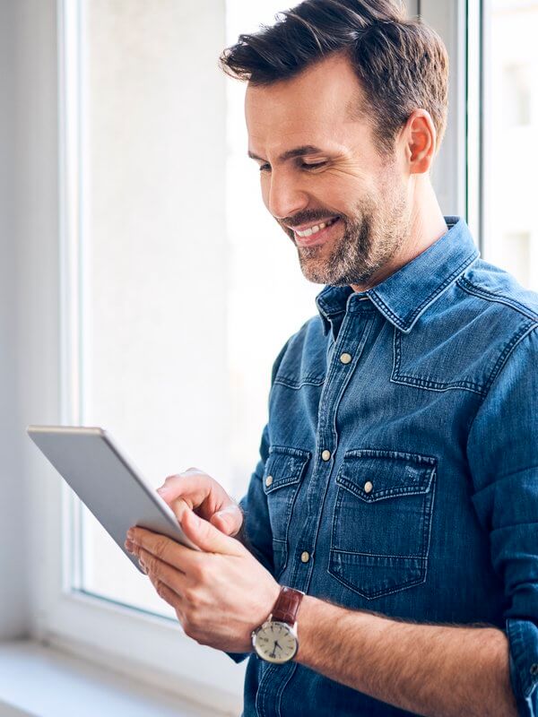 Man smiling while looking at a tablet