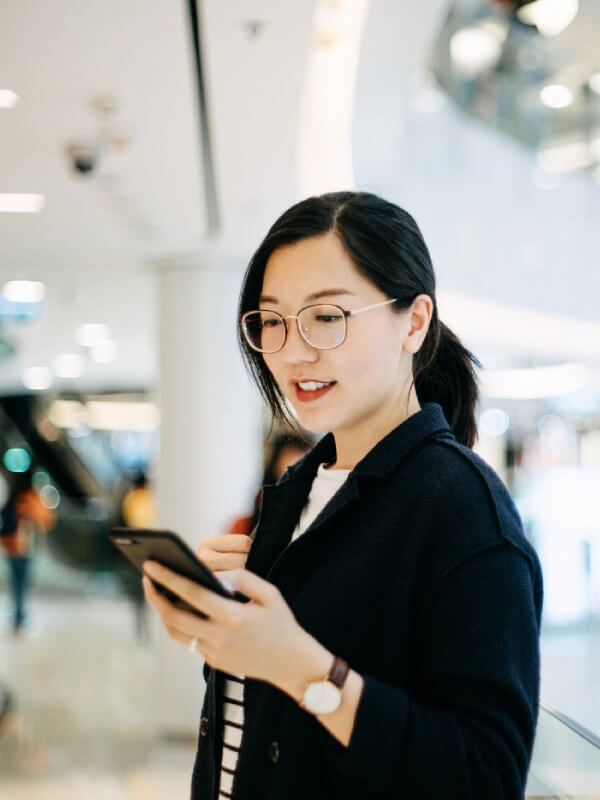 Young woman entering her address details into her phone while out shopping