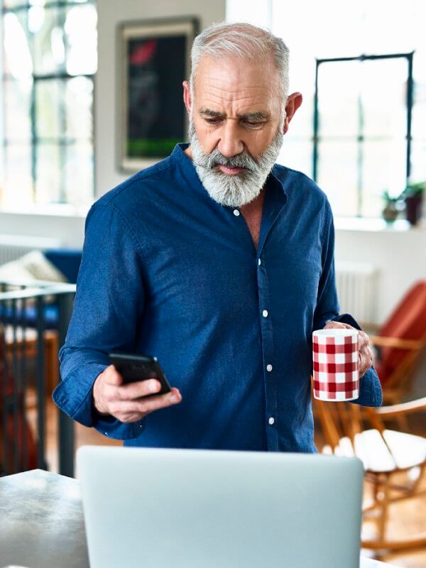 Man at home using his laptop and phone to check application