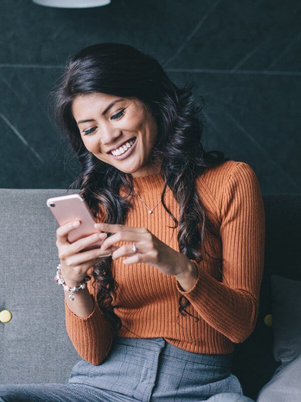 Woman smiling while reading her phone