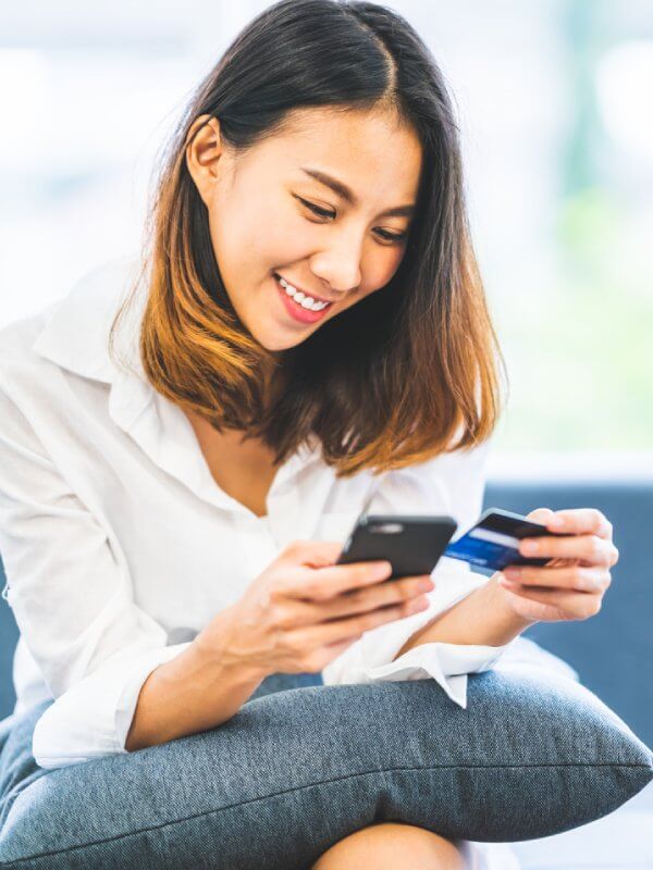 Woman smiling holding her credit card and mobile phone
