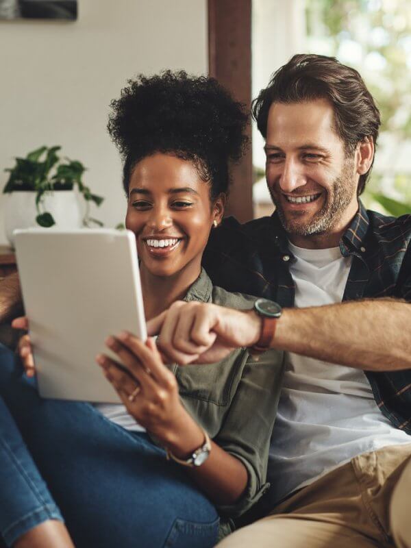 Couple smiling while looking on tablet