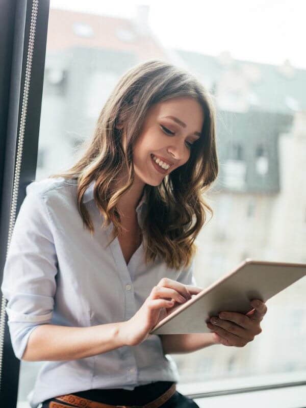 Young woman smiling while using a tablet