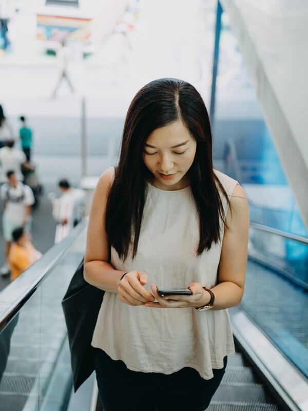 Young woman using her phone on an escalator