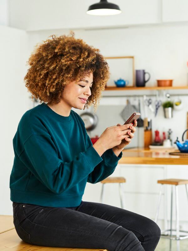 Woman in her kitchen applying for credit on her mobile phone