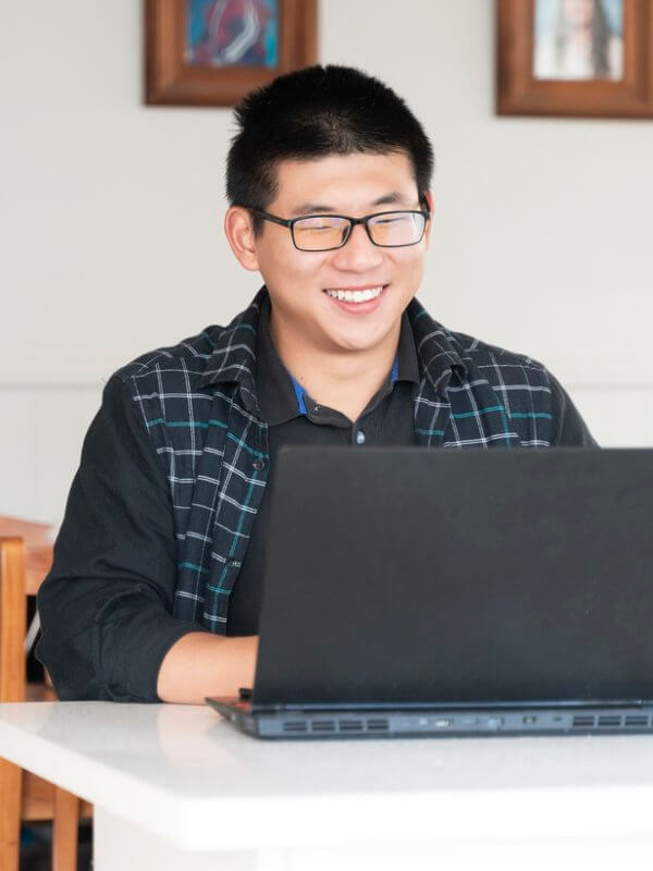 Man smiling while browsing on laptop