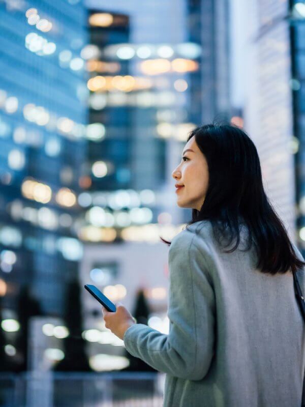Woman using her mobile phone looking at an office building