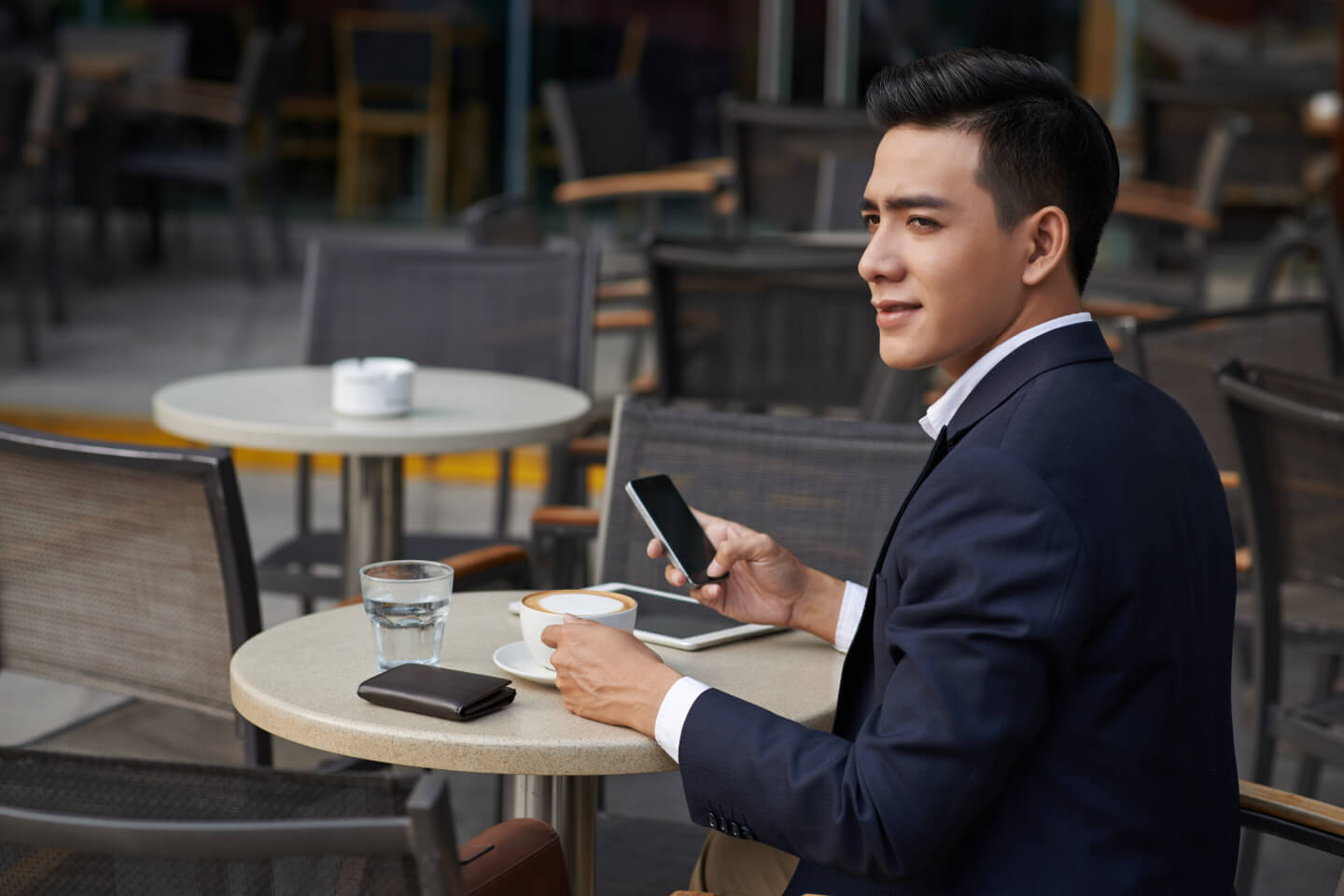 Man in suit sat at table with phone and tablet