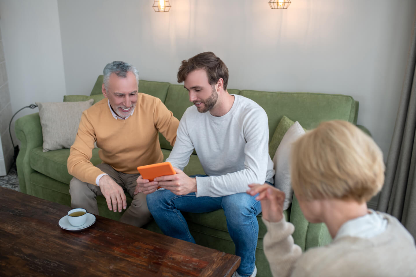 man sat with older couple showing something on a device