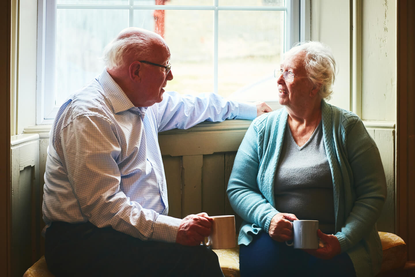 Elderly couple sat in front of a window