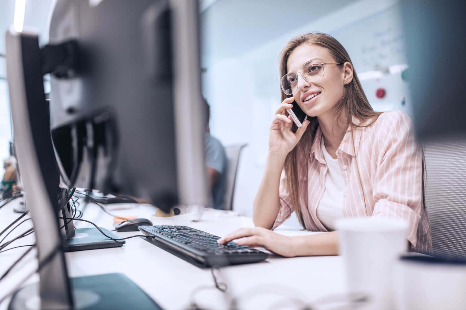 A woman on the phone looking at a computer screen